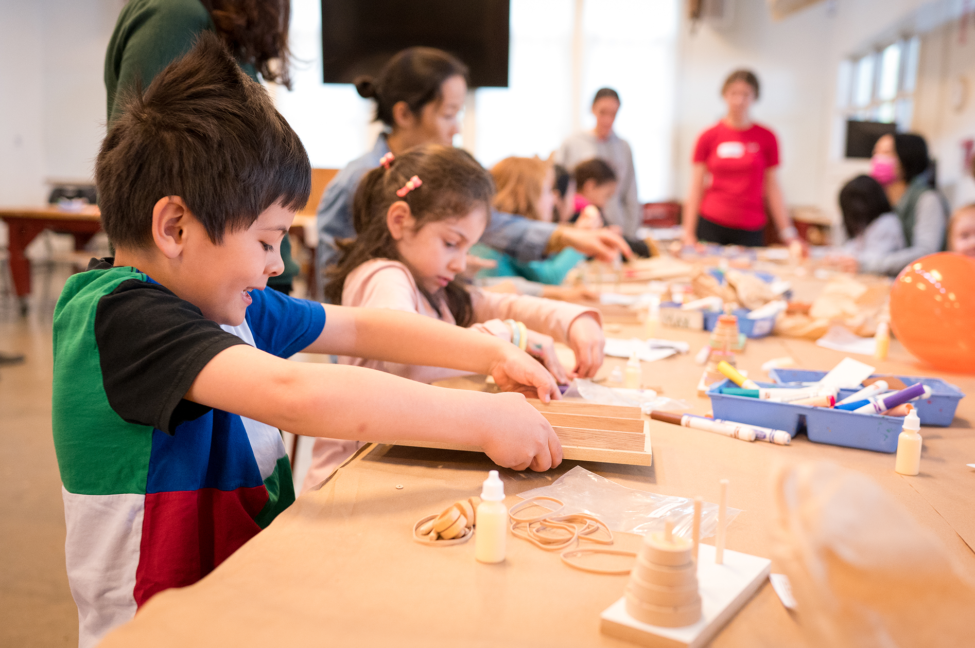 Children sitting at long table building projects.