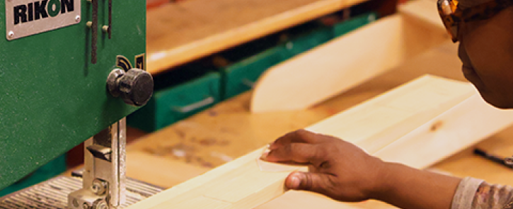 Person cutting a board on a band saw.