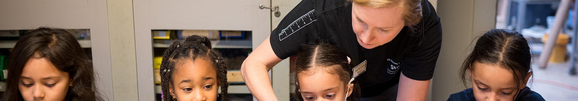 Four students building projects with an educator assisting one of the students.